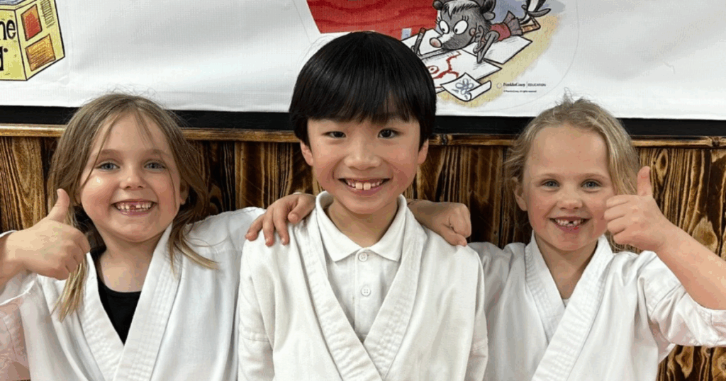 Children smiling and giving thumbs up at Kicx Academy after learning about confidence and positive mindset