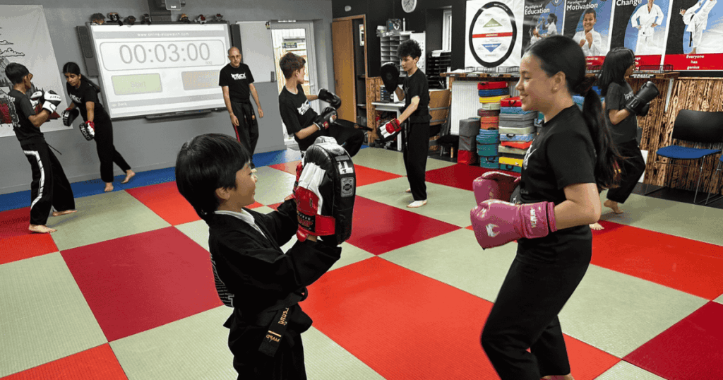 Girl and boy smiling at Kicx Academy Gloucester martial arts class, building confidence and focus