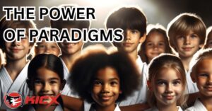 Group of smiling children in martial arts uniforms at Kicx Academy, representing the importance of changing paradigms to build confidence and focus.