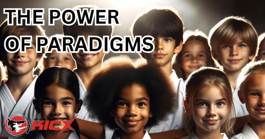 Group of smiling children in martial arts uniforms at Kicx Academy, representing the importance of changing paradigms to build confidence and focus.
