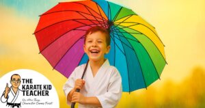Child in karate uniform smiling under a rainbow umbrella in the rain, symbolising confidence and resilience taught at Kicx Academy in Gloucester.